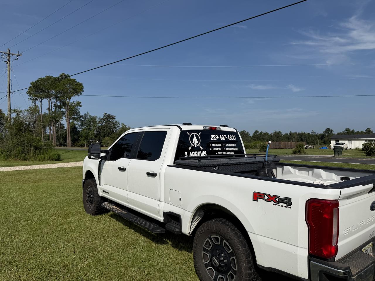 White Ford Super Duty work truck with the 3 Arrows Solutions logo and phone number on the rear window